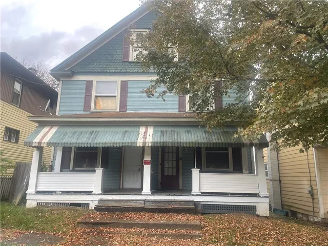 a view of a white house with large windows and a large tree