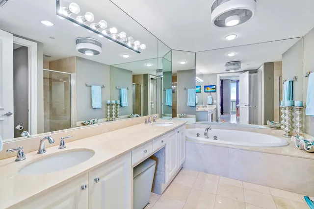a spacious bathroom with a sink double vanity granite tub shower and a mirror