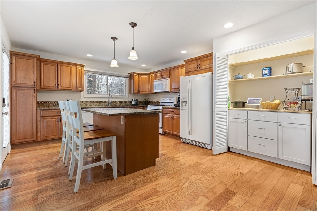 a kitchen with kitchen island granite countertop wooden floors and white cabinets