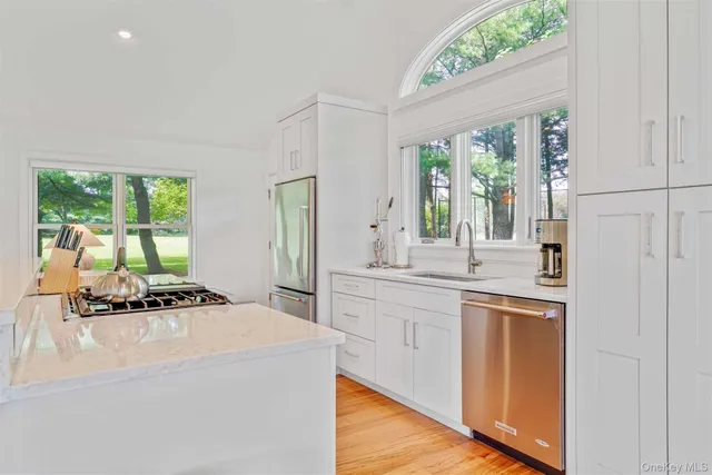 a kitchen with a stove a sink a refrigerator and a view of living room