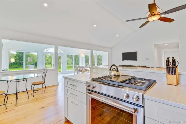 a kitchen with a stove a sink a dining table and chairs with wooden floor