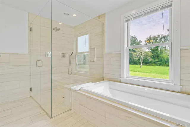 a bathroom with a large tub a shower and view
