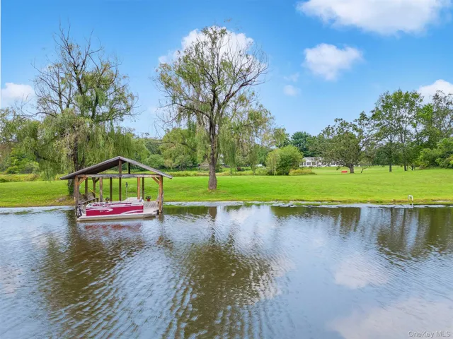 a view of a lake with a yard and large trees