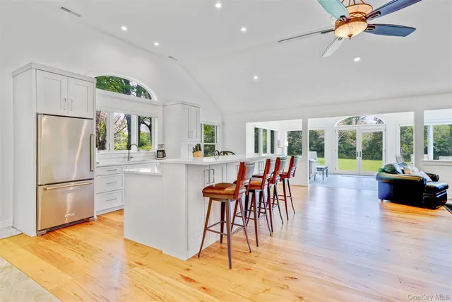 a kitchen with stainless steel appliances granite countertop a refrigerator a microwave oven a dining table and chairs with wooden floor