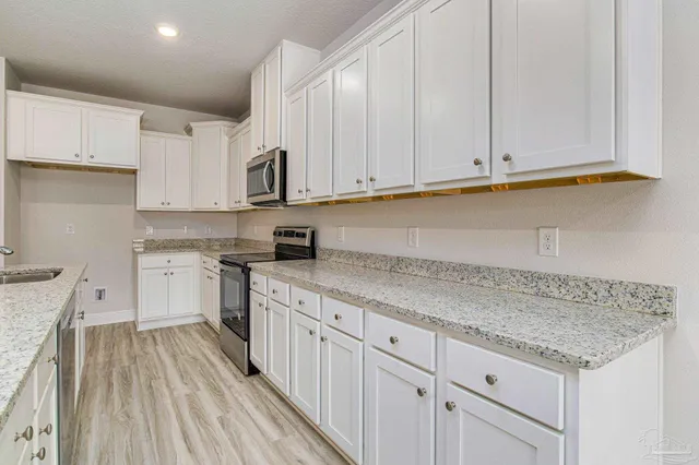 a kitchen with granite countertop white cabinets and white appliances