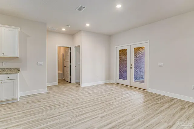 a view of an empty room with wooden floor and cabinets