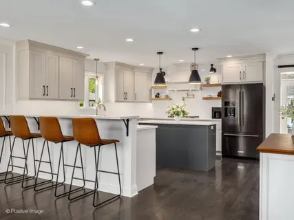 a kitchen with stainless steel appliances granite countertop a refrigerator a stove a sink and white cabinets with wooden floor