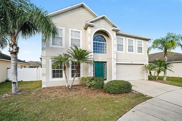 a view of a white house with large windows and a yard with plants