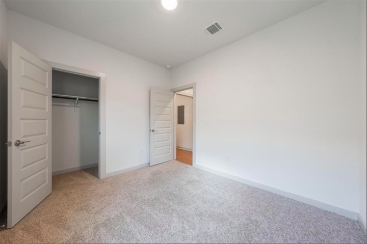 10805 Meris Lane Austin, TX 78754 - Photo 16 of 28 A well-lit bedroom features plush carpeting and convenient closet access, perfect for comfortable living.
