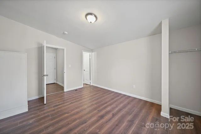a view of an empty room with wooden floor and closet
