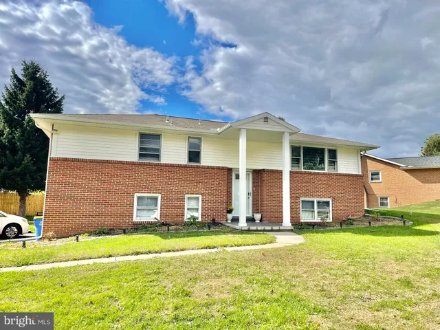 a living room with furniture a potted plant and kitchen view