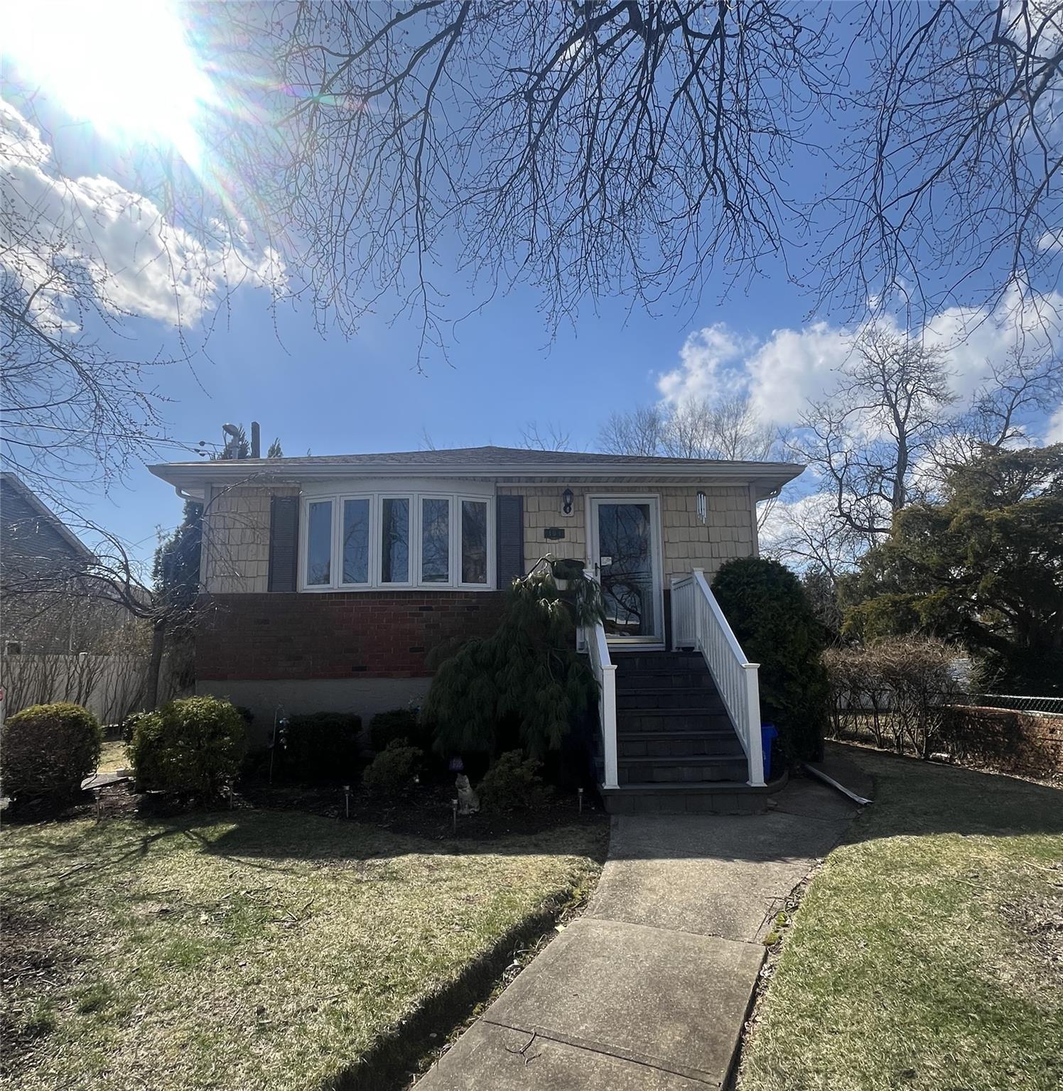 View of front of house featuring a front lawn, fence, and brick siding