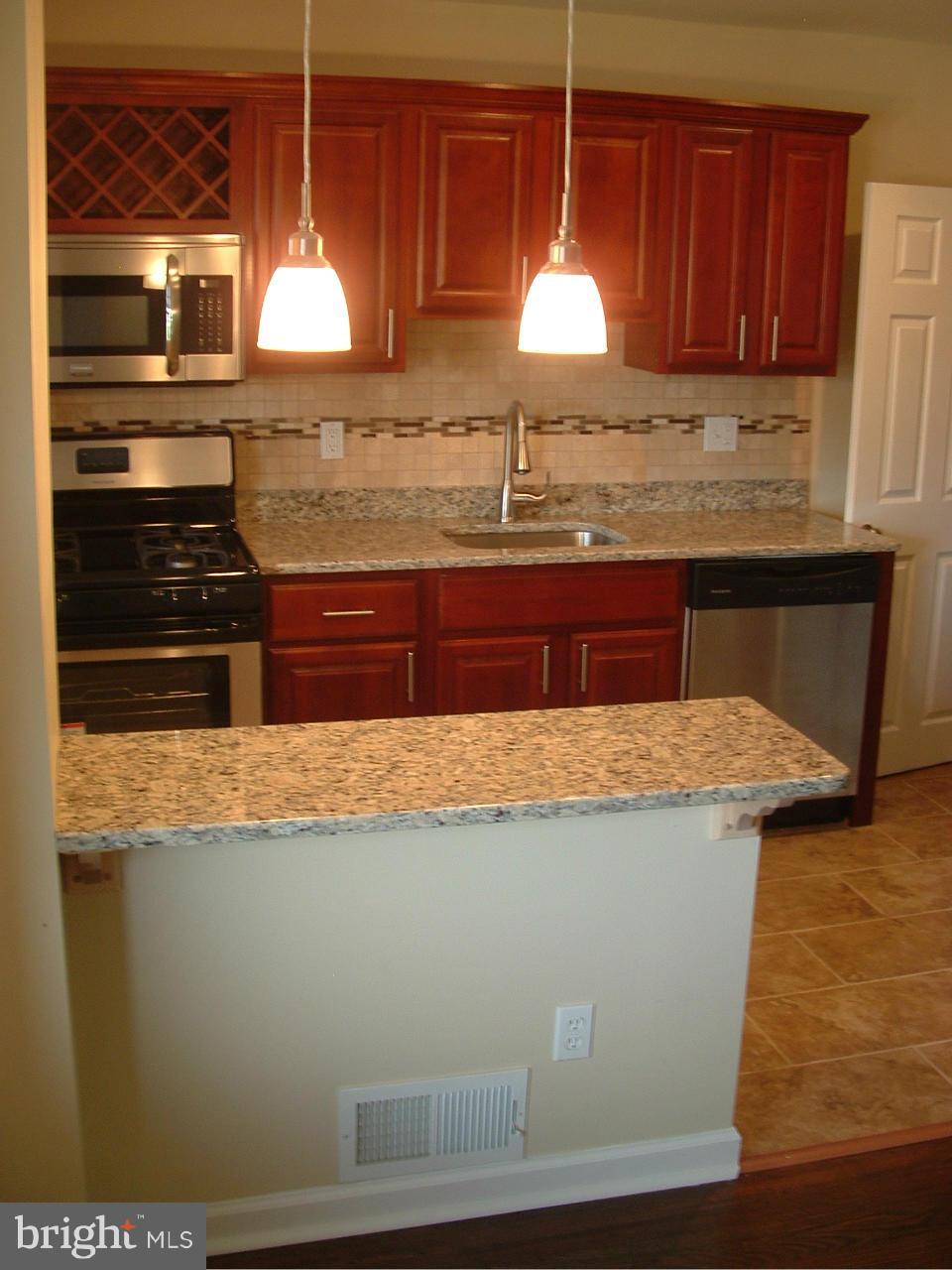 338 Torner Road Baltimore, MD 21221 - Photo 4 of 30 a kitchen with granite countertop wooden cabinets and white appliances