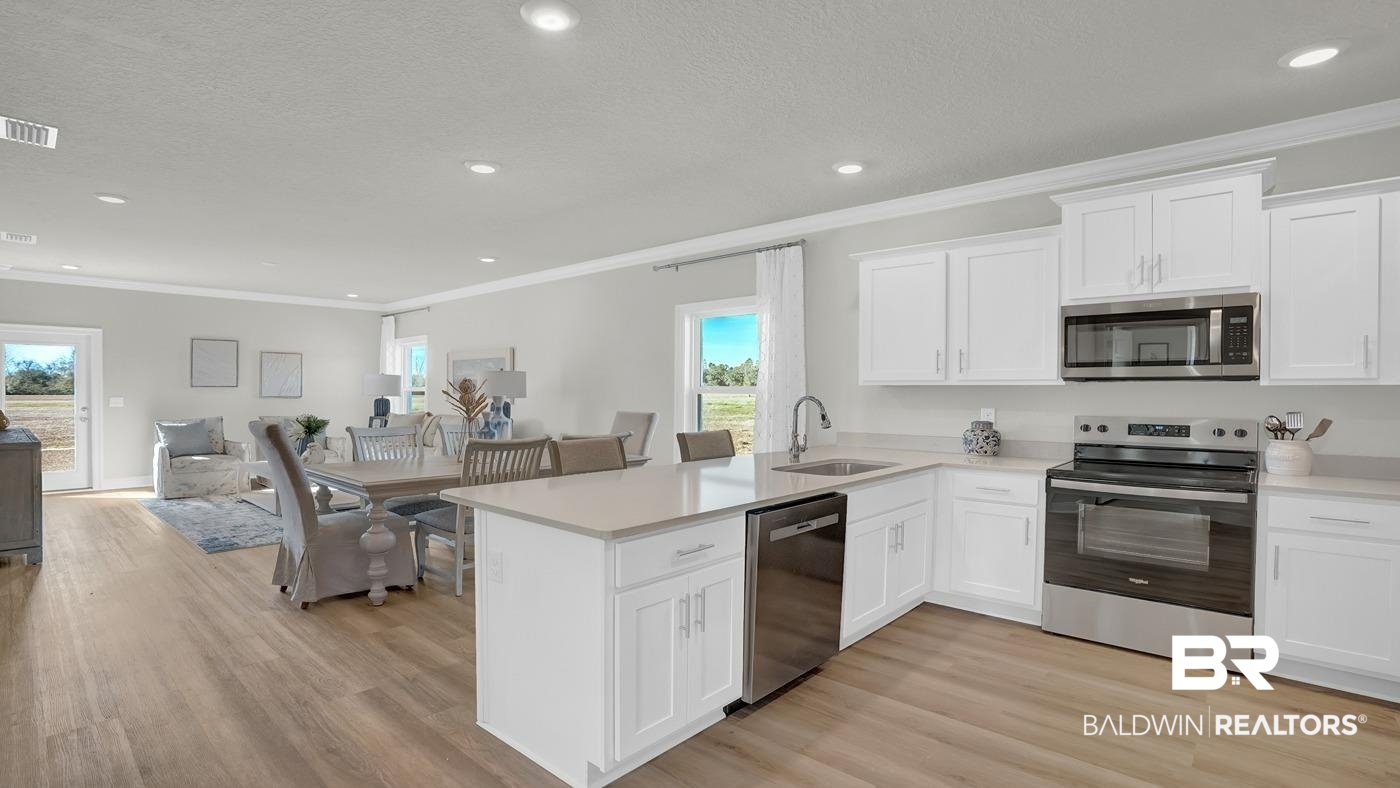13312 Shea Circle Foley, AL 36535 - Photo 4 of 17 Kitchen with white shaker cabinetry, stainless steel appliances, light-toned countertops, and wood-finish flooring