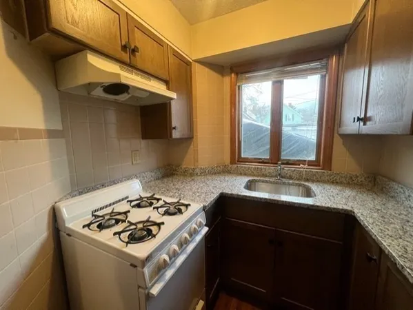 a kitchen with granite countertop a sink stainless steel appliances wooden floor and a counter top space