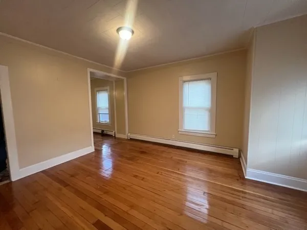 a view of an empty room with window and wooden floor