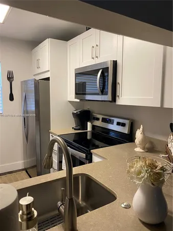 a kitchen with stainless steel appliances a sink a stove a microwave a refrigerator and cabinets