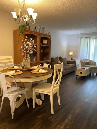 a dining room with furniture a chandelier and wooden floor