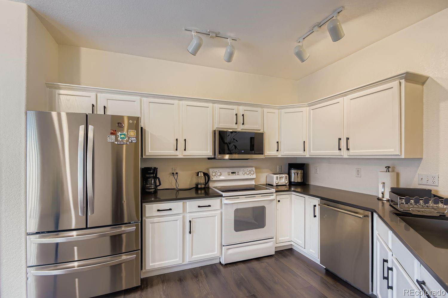 Undisclosed Address Aurora, CO 80013 - Photo 7 of 20 a kitchen with white cabinets and stainless steel appliances
