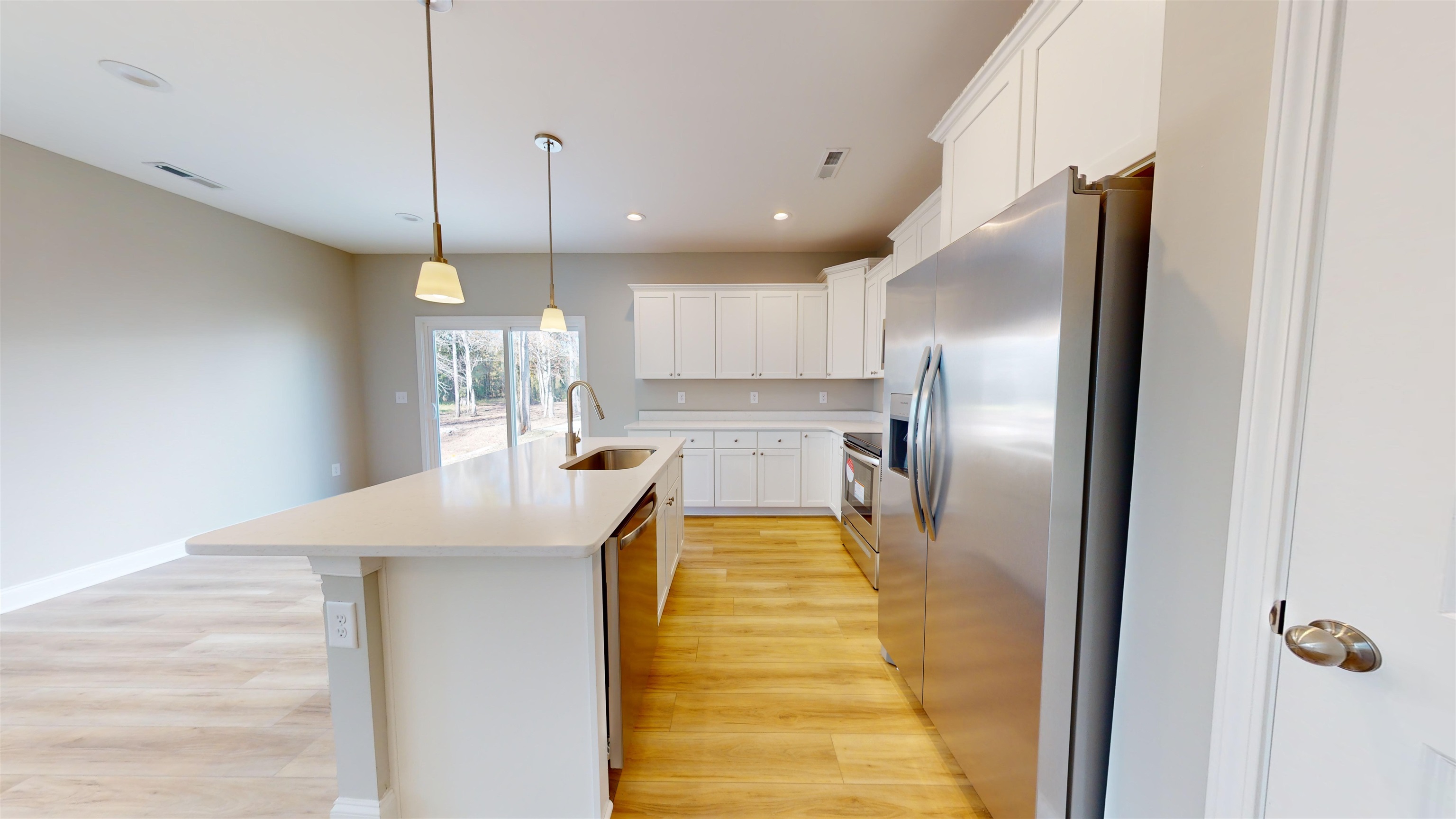 1032 Moen Loop, Unit LOT 9 Conway, SC 29526 - Photo 9 of 36 Kitchen with stainless steel appliances, white cabinets, decorative light fixtures, light wood-type flooring, and a kitchen island with sink