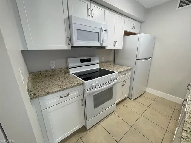 a kitchen with white cabinets and white appliances
