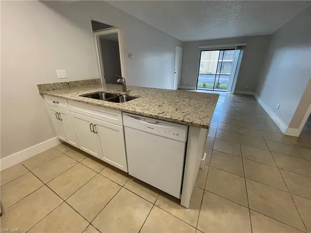 a kitchen with granite countertop white cabinets and window