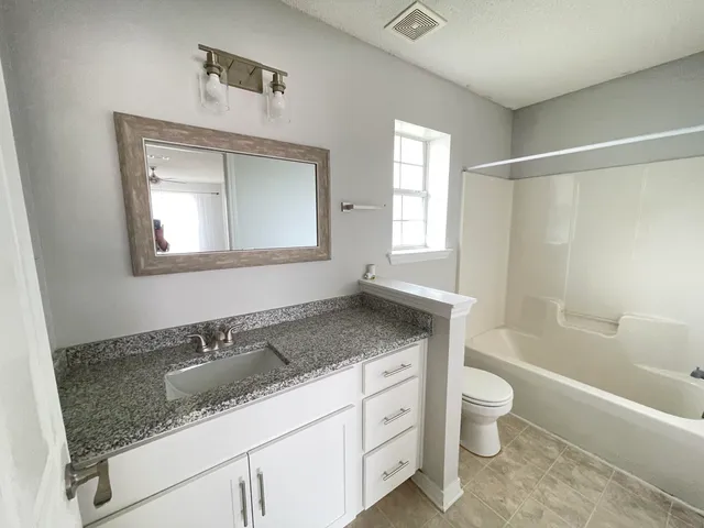 a bathroom with a granite countertop sink a toilet and bathtub