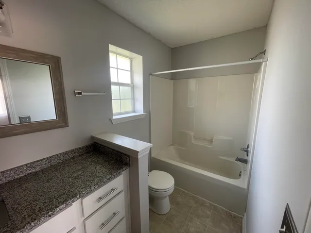 a bathroom with a granite countertop sink toilet and shower