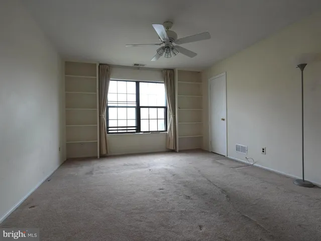 an empty room with windows and ceiling fan