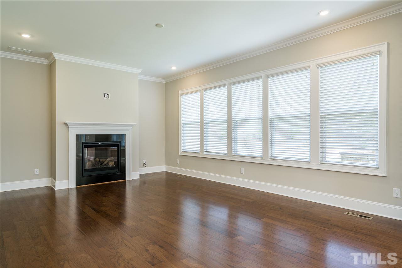 5928 Bellona Lane Raleigh, NC 27612 - Photo 12 of 25 an empty room with wooden floor and a fireplace