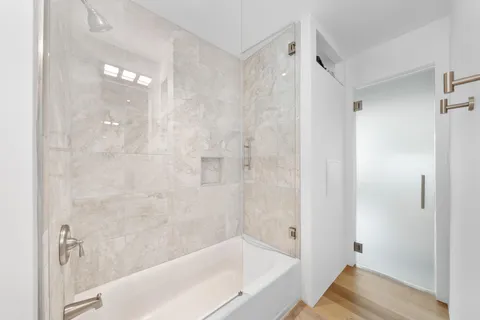 a bathroom with a granite countertop sink a mirror bathtub and shower