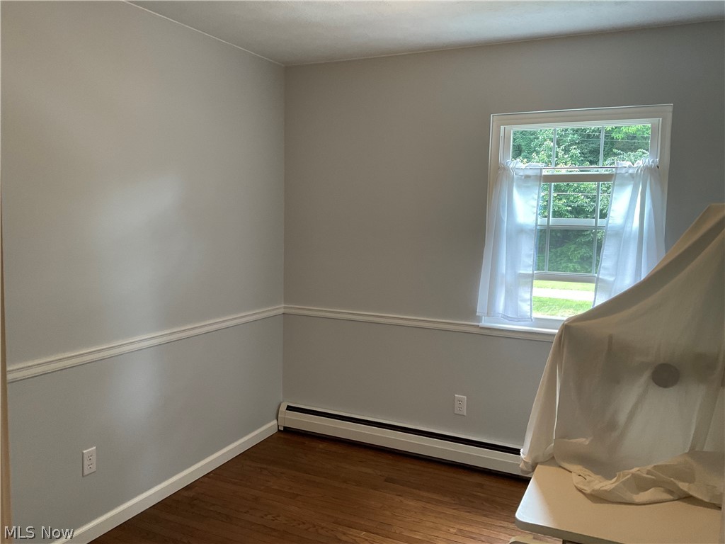 5360 Chapel Road Madison, OH 44057 - Photo 20 of 34 Unfurnished room featuring baseboard heating, dark hardwood / wood-style flooring, and plenty of natural light