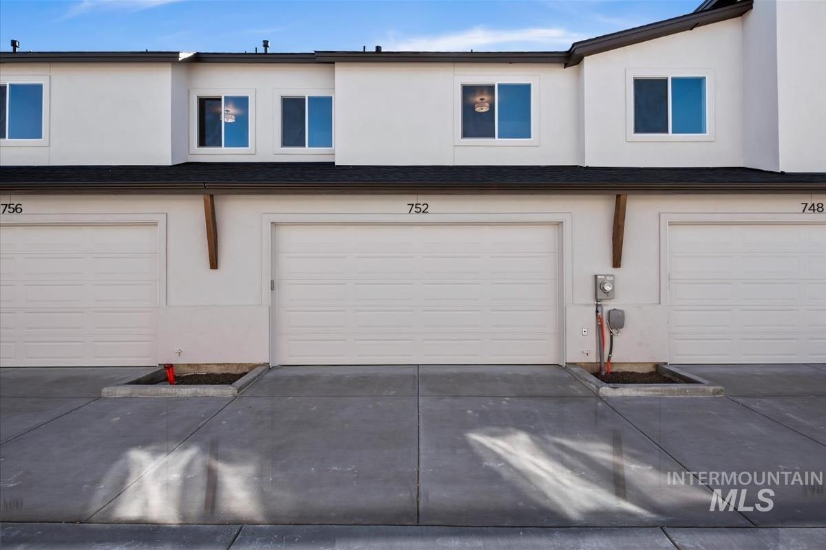 752 South Calhoun Lane Star, ID 83669 - Photo 36 of 45 Modern townhome exterior featuring white stucco siding, a dark shingle roof, and white-framed windows