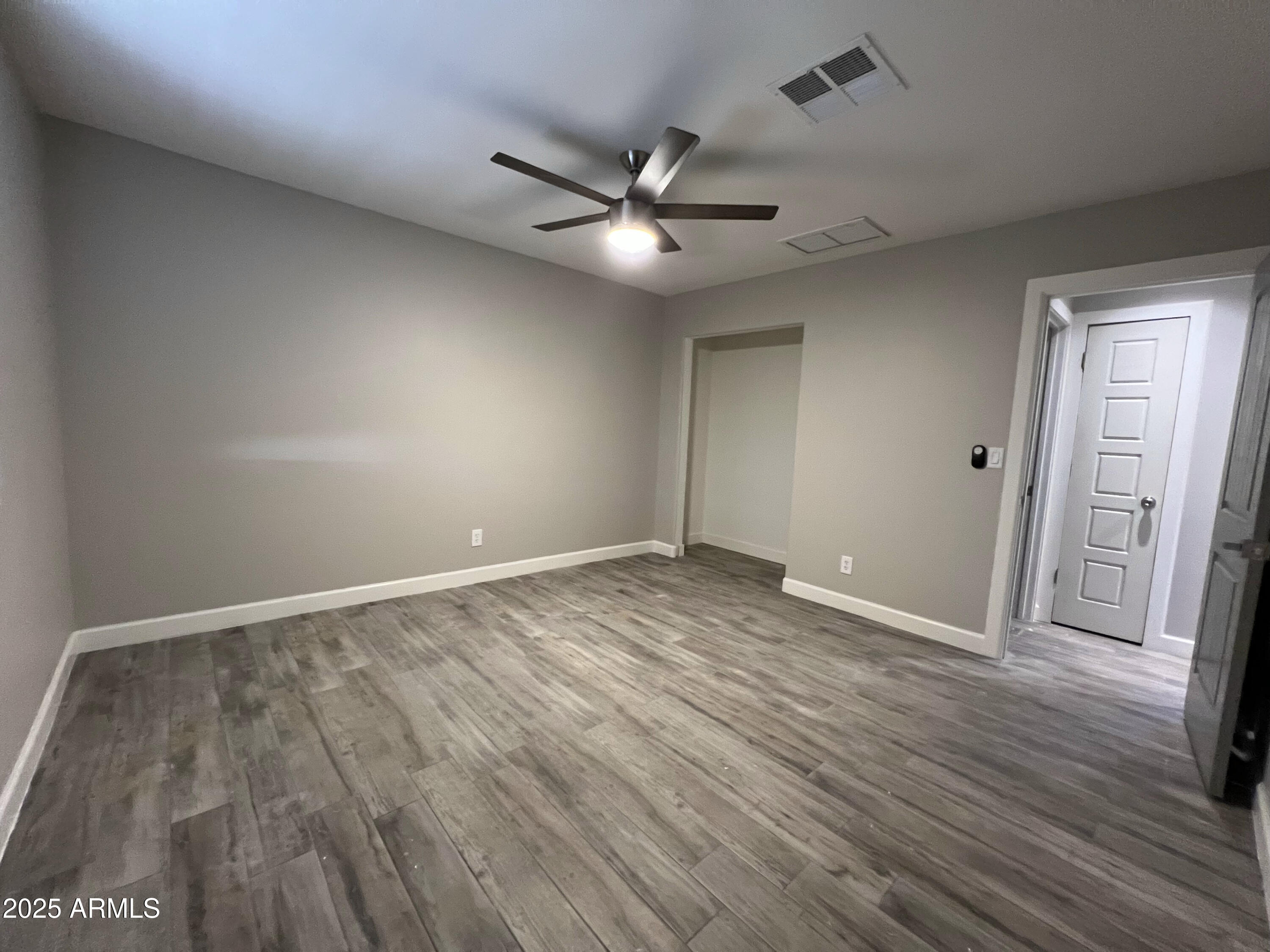 8201 South 26th Street Phoenix, AZ 85042 - Photo 18 of 42 an empty room with wooden floor and a ceiling fan