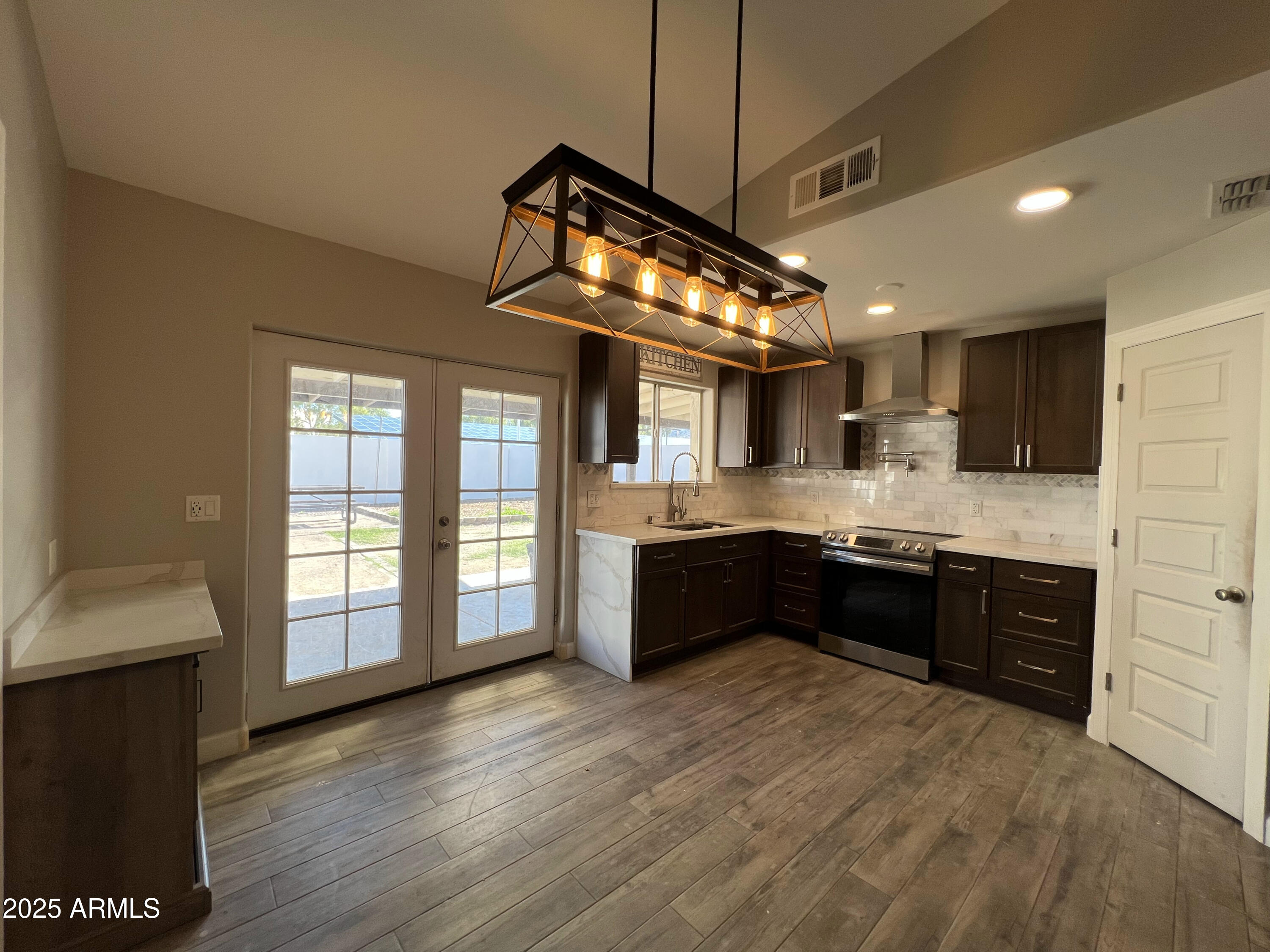 8201 South 26th Street Phoenix, AZ 85042 - Photo 6 of 42 a large kitchen with stainless steel appliances granite countertop a stove a sink dishwasher a refrigerator and wooden floor