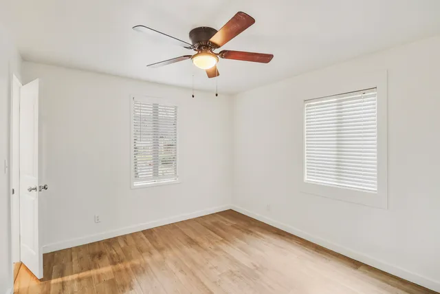 a view of an empty room with wooden floor and a window