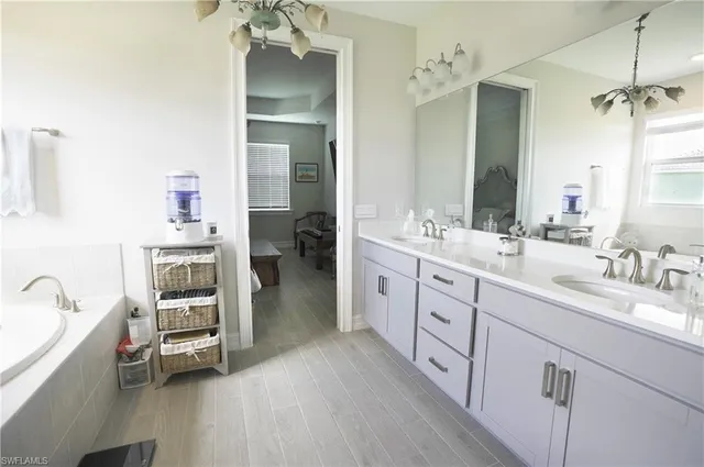 a spacious en suite bathroom with a double vanity sink a large mirror and a bathtub