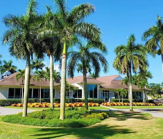 a view of a white house with a swimming pool and a lawn chairs under palm trees