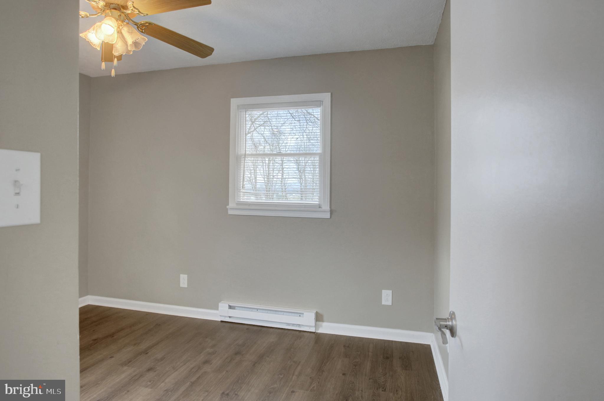 16944 Shinham Road Hagerstown, MD 21740 - Photo 15 of 29 an empty room with wooden floor chandelier fan and windows