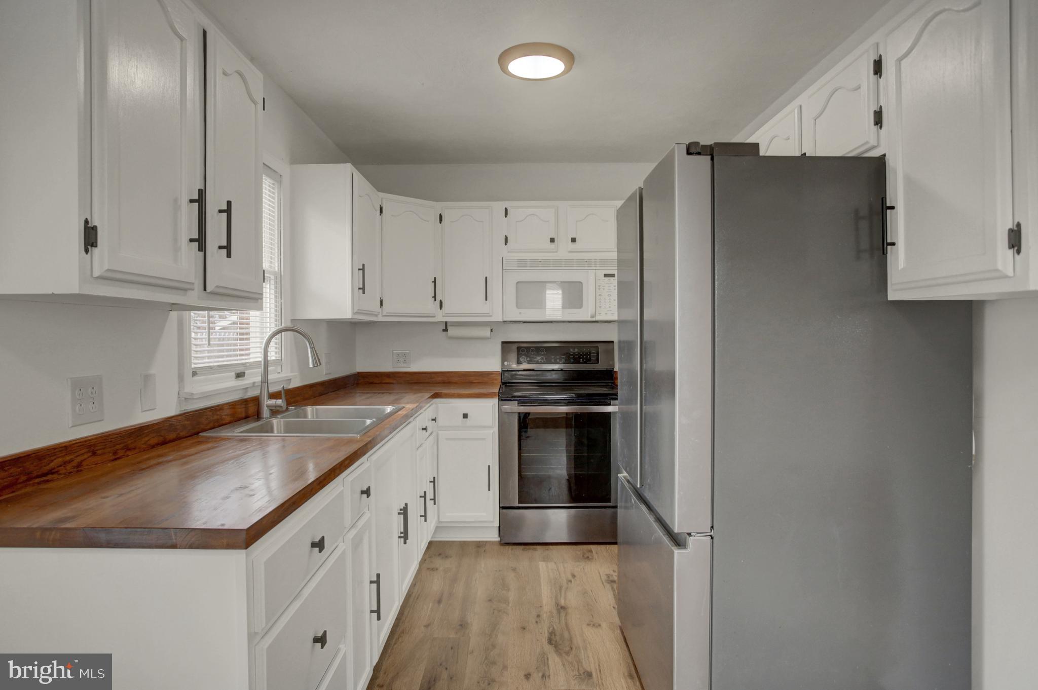 16944 Shinham Road Hagerstown, MD 21740 - Photo 5 of 29 a kitchen with granite countertop a refrigerator sink and white cabinets