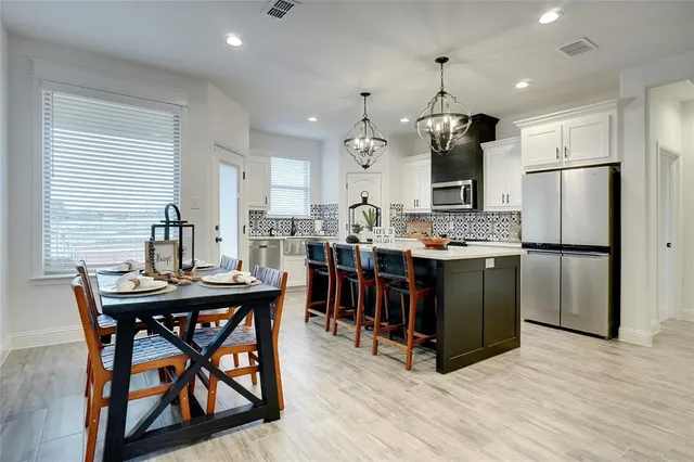 a kitchen with stainless steel appliances kitchen island granite countertop a table chairs and a refrigerator