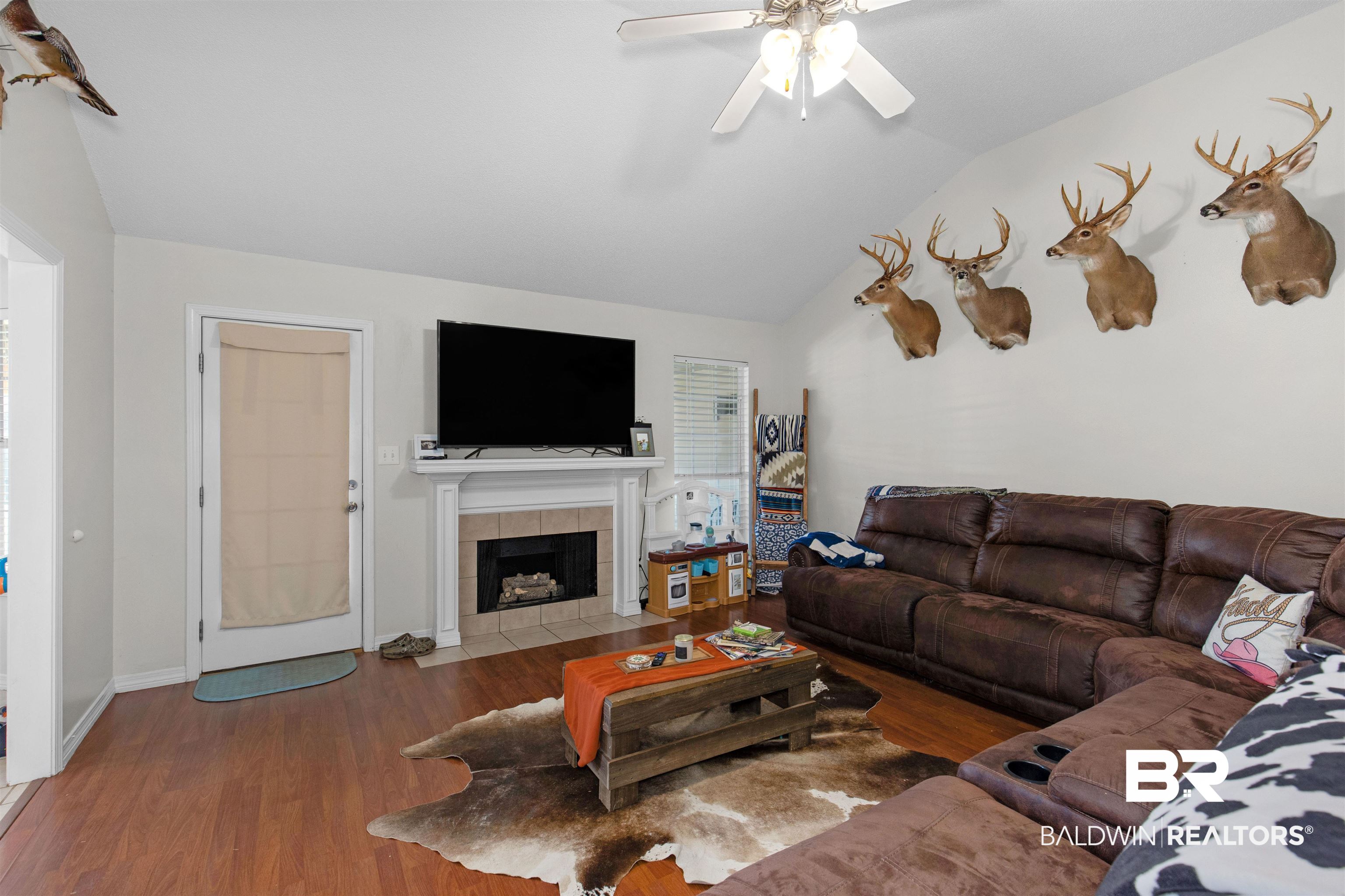 4950 Clealand Court Mobile, AL 36695 - Photo 3 of 20 Living room featuring lofted ceiling, ceiling fan, a tile fireplace, wood finished floors, and baseboards