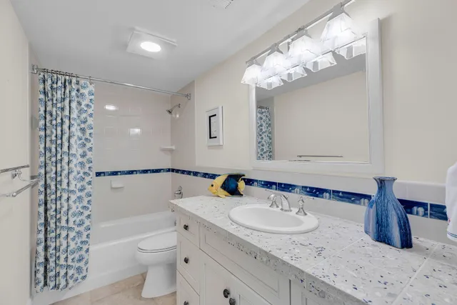 a bathroom with a granite countertop sink a toilet a mirror and shower