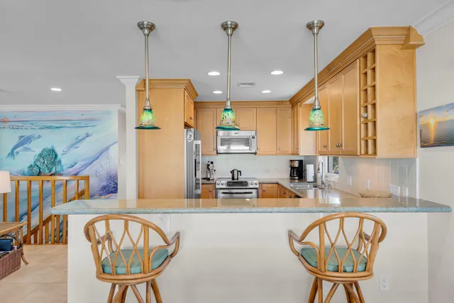 a kitchen with stainless steel appliances granite countertop a refrigerator a sink a stove and a dining table with wooden cabinet