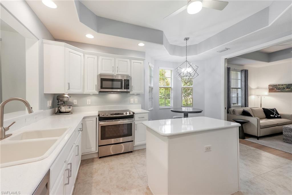 7849 Hawthorne Drive, Unit 802 Naples, FL 34113 - Photo 11 of 49 Kitchen with a raised ceiling, sink, hanging light fixtures, white cabinetry, and stainless steel appliances