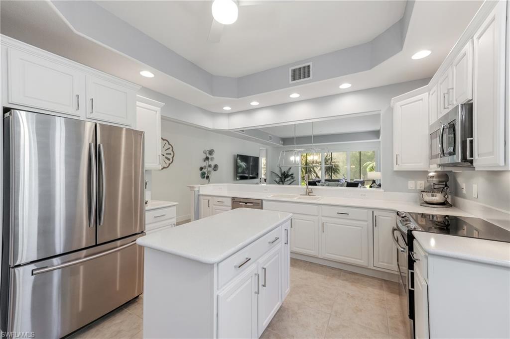 7849 Hawthorne Drive, Unit 802 Naples, FL 34113 - Photo 2 of 49 Kitchen with kitchen peninsula, stainless steel appliances, a kitchen island, light tile patterned floors, and white cabinetry