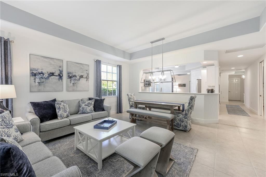 7849 Hawthorne Drive, Unit 802 Naples, FL 34113 - Photo 8 of 49 Living room featuring a raised ceiling, an inviting chandelier, and light tile patterned flooring