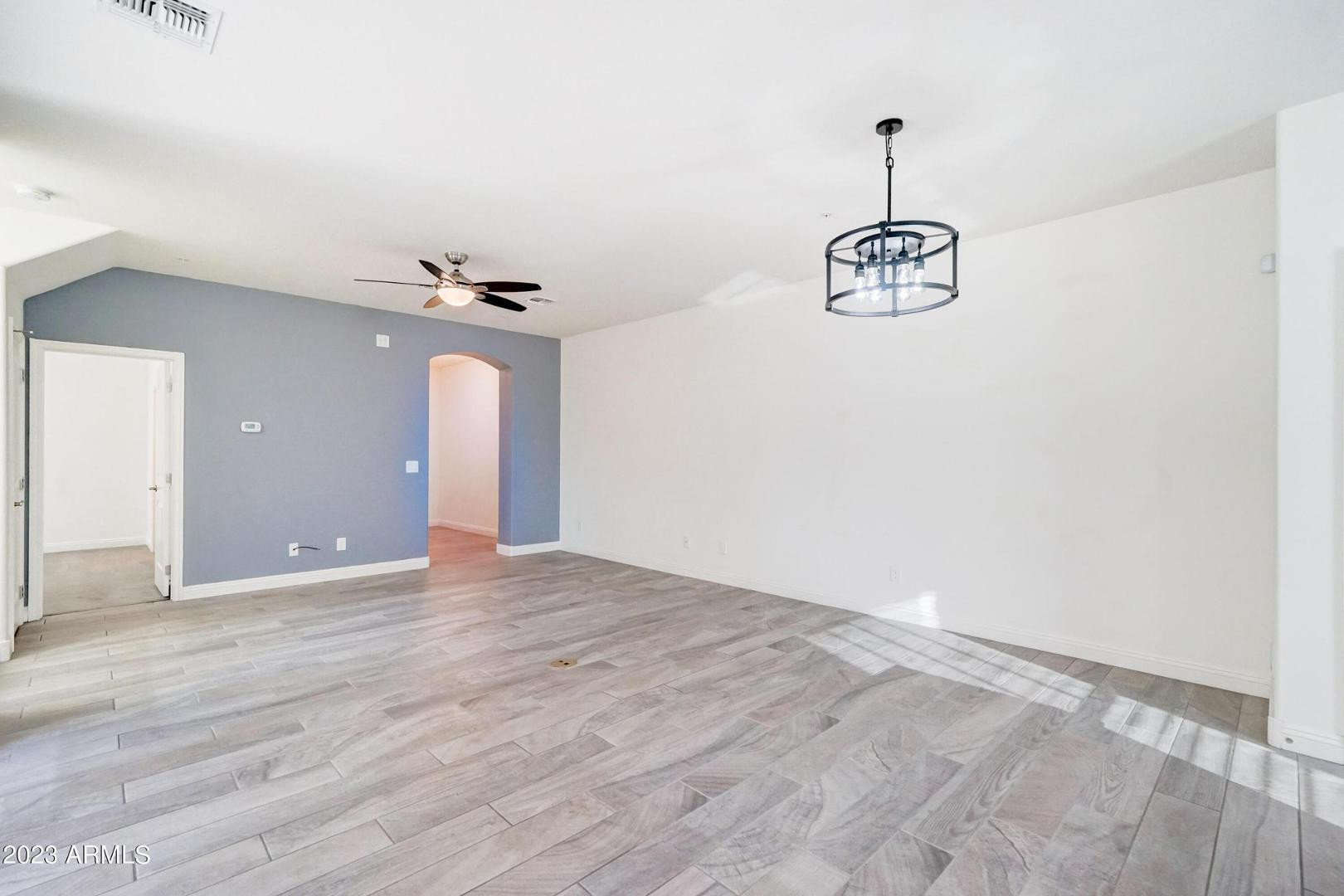2297 North Alsap Road Buckeye, AZ 85396 - Photo 7 of 36 a view of a room with a chandelier fan and wooden floor