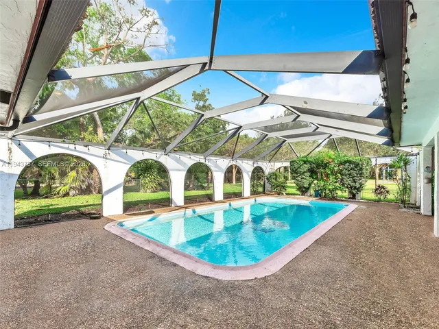 a view of an empty room with kitchen and a window