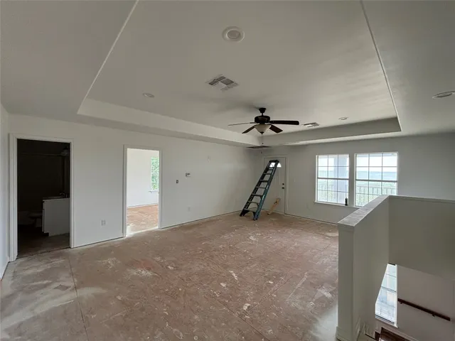 en empty room with windows and ceiling fan
